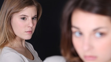 Eine junge Frau sieht neidisch zu einer anderen Frau. | Bild: Colourbox.com/Phovoir
