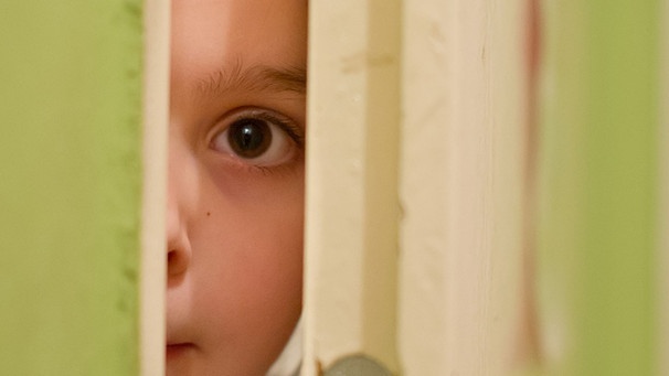 Neugieriges Kind blickt durch den Türspalt | Bild: picture-alliance/dpa