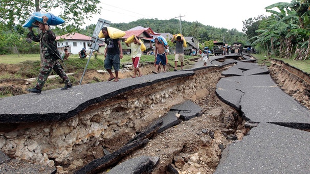An einer vom Erdbeben (2012) zerstörten Straße auf den Philippinen tragen Soldaten und Zivilisten Reissäcke. | Bild: picture-alliance/dpa