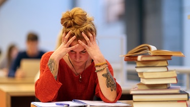 Junge Frau sitzt verzweifelt vor einer Prüfungsaufgabe | Bild: picture-alliance/dpa