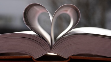 Die Seiten eines aufgeschlagenen Buches sind zu einem Herz gefaltet. | Bild: picture alliance / imageBROKER | Siegfried Kramer