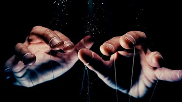 Zwei Hände mit Fäden um die Finger wie bei einer Marionette. | Bild: stock.adobe.com/sp3n