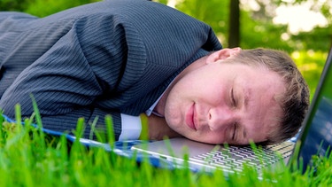 Mann mit Anzug schläft auf Laptop in einer Wiese | Bild: colourbox.com