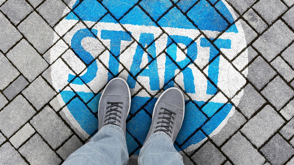 Füße stehen auf einem Schild am Boden mit dem Wort "Start" | Bild: picture alliance / Zoonar | DesignIt