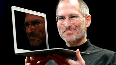 Steve Jobs hebt lächelnd das neue MacBook Air hoch | Bild: picture-alliance/dpa