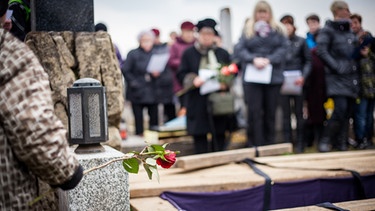 Trauernde stehen bei einer Beerdigung um ein Grab herum. | Bild: stock.adobe.com/mdennah