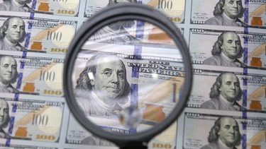 frischgedruckte Dollarnoten werden mitder Lupe angeschaut | Bild: picture-alliance/dpa