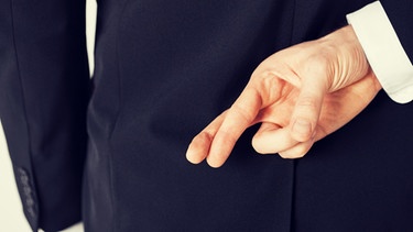 Ein Mann kreuzt seine Finger hinter seinem Rücken | Bild: colourbox.com