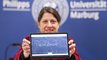 Constanze Spieß präsentiert «Pushback» , das «Unwort des Jahres» 2021, auf
einem iPad bei einer Pressekonferenz an der PhilippsUniversität Marburg. | Bild: dpa-Bildfunk/Nadine Weigel