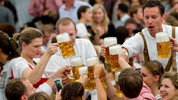 Wiesnbesucher feiern in einem Bierzelt auf dem Oktoberfest in München nach dem Anzapfen mit ihrer ersten Maß (Archivbild). | Bild: picture-alliance/dpa/Sven Hoppe