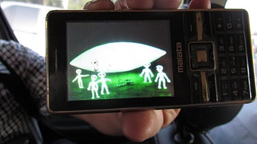 Auf Mobiltelefon: Fünf Außerirdische und ein UFO  - Symbolbild  | Bild: picture alliance_dpa_Chen Xuechao