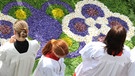 Ministranten warten an Fronleichnam während der Prozession an einem Blumenteppich | Bild: picture-alliance/dpa