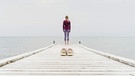 Eine Frau steht auf einem Pier, im Vordergrund sieht man ihre Schuhe | Bild: picture alliance / Westend61 | Christophe Papke