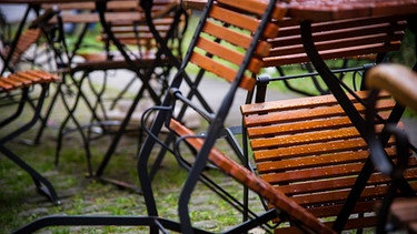 Die vom Regen naßen Holzstühle eines Cafes in Bamberg (Bayern) sind am 27.06.2013 zusammengestellt. | Bild: picture-alliance/dpa
