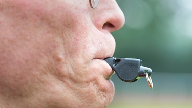 Schiedsrichter mit einer Trillerpfeife im Mund | Bild: picture-alliance/dpa