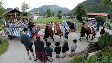 Eine Familie in Trachten verfolgt am Sonntag (26.08.2012) beim traditionellen Rosstag in Rottach-Egern am Tegernsee (Oberbayern) die vorbeifahrende Pferdekutsche. Die Veranstaltung unter dem Motto «d'Fuhrleut kemman z'amm» ist eine Tourismusattraktion im bayerischen Oberland.  | Bild: picture-alliance/dpa