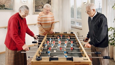 Drei Senioren spielen in einem Heim der Diakonie Neuendettelsau Kicker | Bild: Diakonie Neuendettelsau