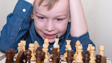Ein Junge sitzt vor einem Schachspiel und hält sich den Kopf | Bild: colourbox.com