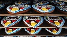 Lebkuchenherzen mit "Oktoberfest"-Schriftzug liegen in der Fabrik zum Auskühlen | Bild: Zuckersucht/Aschheim