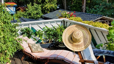 Idylle auf einem sonnigen Holzbalkon mit Sonnenhut. | Bild: stock.adobe.com/ArTo