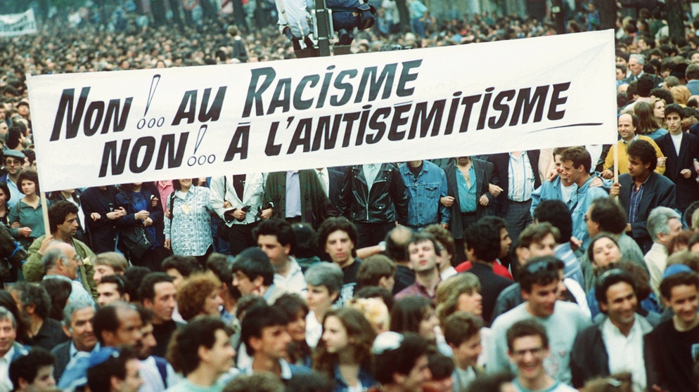Demonstranten mit einem Transparent "Nein zu Rassismus - Nein zu Antisemitismus". Nach Grab- und Leichenschändungen in Carpentras wurden Gräber auf dem Friedhof von Clichy mit Hakenkreuzen beschmiert. In Paris fand daraufhin eine Demonstration gegen den Antisemitismus statt. Aufgenommen am 14. Mai 1990. | Bild: picture-alliance  dpa  AFP