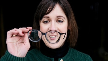 Eva Karl-Faltermeier schaut verschmitzt ihre Brille an | Bild: Florian Hammerich