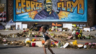 Ein Kind spielt vor einem Graffiti, in dem an George Floyd gedacht wird | Bild: picture-alliance/dpa