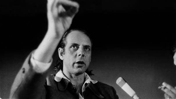 Der Komponist Karlheinz Stockhausen blickt nach oben, in seiner erhobenen Hand hält er eine Zigarette.  | Bild: picture alliance / Philippe Gras / Le Pictorium