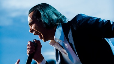 Nick Cave auf der Bühne mit Fans und Mikrofon | Bild: picture alliance / Photoshot | -