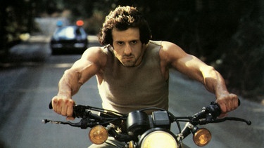Sylvester Stallone auf einem Motorrad, Szene aus "Rambo: First Blood" | Bild: picture alliance / Mary Evans/AF Archive/Thorn Emi | AF Archive