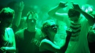 Tanzende Menschen im grünen Licht | Bild: dpa/Picture Alliance