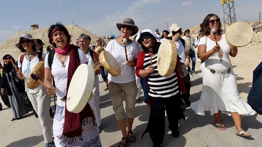 Vor kiesigem Hintergrund maschieren Frauen. Einige trommeln, sie tragen Hüte und lachen. Israelische und palästinensischen Frauen demonstrieren gemeinsam 2016, organisiert von "Woman Wage Peace" | Bild: picture alliance / newscom | DEBBIE HILL