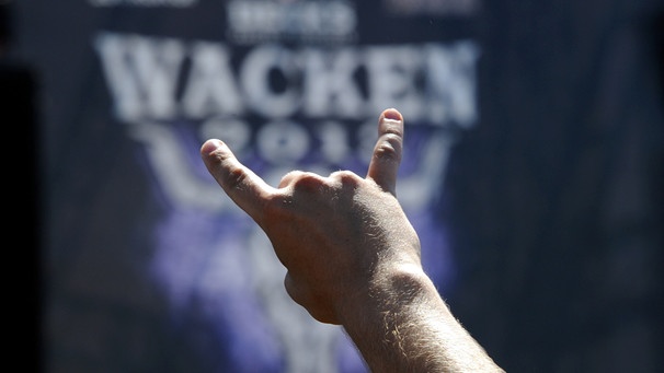 Ein Festivalbesucher zeigt auf dem Festivalgelände in Wacken (Schleswig-Holstein) das Zeichen der Heavy-Metal-Fans, die "Pommesgabel" | Bild: picture alliance / dpa | Carsten Rehder