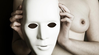 Frau, die sich eine ausdruckslose Gesichtsmaske vor die nackte Brust hält. | Bild: picture-alliance/dpa