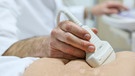 Ein Arzt untersucht die Bauchdecke eines Mannes mittels Ultraschall. | Bild: picture-alliance/dpa