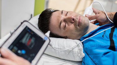 Ein Patient wird mit einem mobilen Ultraschallgerät am Hals untersucht. | Bild: picture-alliance/dpa