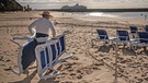 Dezember 2020, Spanien, Tenerriffa: Ein Mann stellt Liegestühle am Strand von Las Teresitas in Santa Cruz de Tenerife auf.  | Bild: picture-alliance/dpa