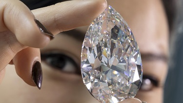 06.05.2022, Schweiz, Genf: Eine Mitarbeiterin von Christie's hält «The Rock», einen weißen Diamanten von 228,31 Karat, der der größte weiße Diamant ist, der jemals in der Geschichte des Auktionsmarktes gesehen wurde, während einer Vorschau bei Christie's in Genf. Der auf 19.000.000 - 30.000.000 CHF (Schweizer Franken) geschätzte Stein wird als Highlight der Genfer Prunkjuwelen-Auktion am 11. Mai 2022 versteigert. Foto: Salvatore Di Nolfi/KEYSTONE/dpa +++ dpa-Bildfunk +++ | Bild: dpa-Bildfunk/Salvatore Di Nolfi