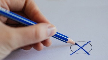 Symbolbild Wahl: Mit einem blauen Buntstift wird ein Kreuz auf einen Wahlzettel gesetzt | Bild: BR