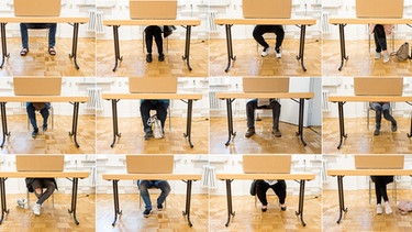 Wähler sitzen in einem Wahllokal in einer Wahlkabine und füllen ihre Stimmzettel zur Europawahl aus | Bild: dpa-Bildfunk