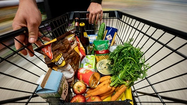 Blick von oben in einen Einkaufwagen mit Supermarkt-Produkten | Bild: picture-alliance/dpa