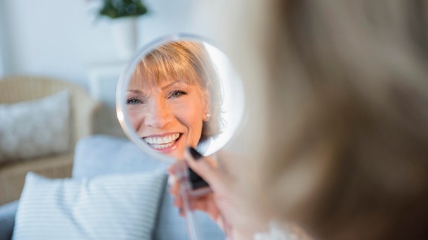 Eine ältere Dame betrachtet ihre Zähne in einem Handspiegel. | Bild: BR-Bild