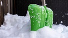 Eine grüne Schneeschaufel steckt im Schnee. | Bild: BR/Raphael Kast