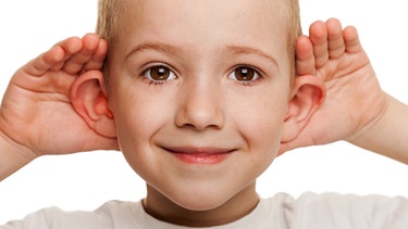 Ein Junge hält sich die Hände an die Ohrmuscheln, um besser zu hören. | Bild: colourbox.com
