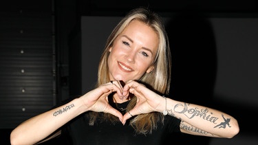 Sängerin Sonia Liebing formt mit ihren Händen ein Herz und lächelt in die Kamera | Bild: picture-alliance/dpa