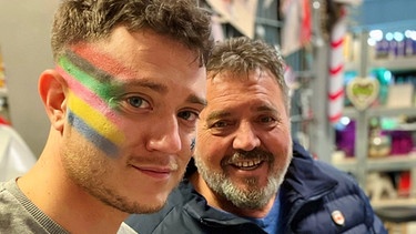 Max Weidner und sein Opa. Max hat eine Regenbogenfahne auf seine Wange gemalt. | Bild: Max Weidner