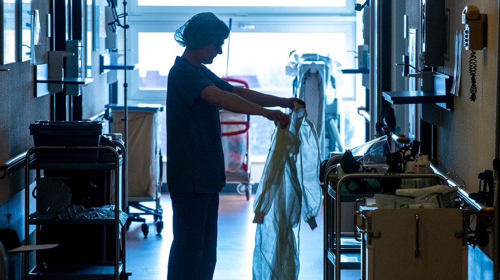 Eine Krankenschwester legt auf der Isolierstation für Coronavirus-Behandlungen einer Klinik Schutzkleidung an. | Bild: dpa-Bildfunk/Jens Büttner