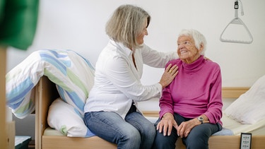 Eine Pflegerin hilft einer Seniorin im Pflegebett. | Bild: BR/Johanna Schlüter