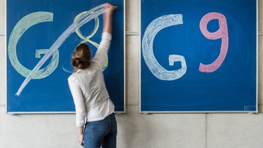 Eine Schülerin der Oberstufe streicht an einem Gymnasium den Schriftzug «G8» an einer Tafel durch, daneben lässt sie «G9» unberührt. | Bild: dpa-Bildfunk/Armin Weigel