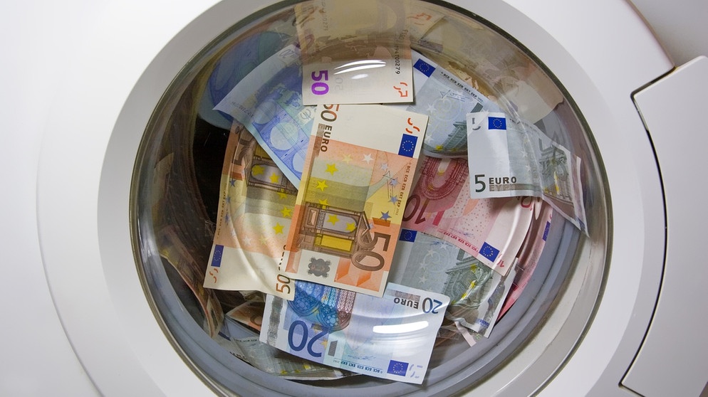 Gelscheine in einer Waschmaschinentrommel als Symbolbild für Geldwäsche. | Bild: stock.adobe.com/Hans und Christa Ede